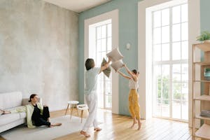 Family enjoying a playful pillow fight in a spacious modern living room. a family enjoying a healthy, well-designed home in the Philippines.